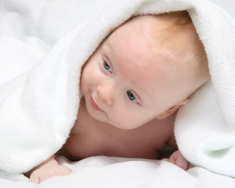 Cute baby wrapped in a soft white towel, symbolizing family care and wellness at AlphaGenics