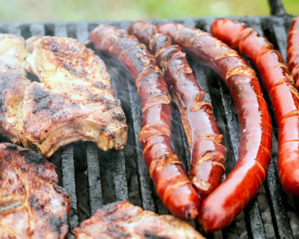 Sizzling steaks and smoked sausages cooking on an outdoor grill for AlphaGenics community BBQ events and wellness lifestyle